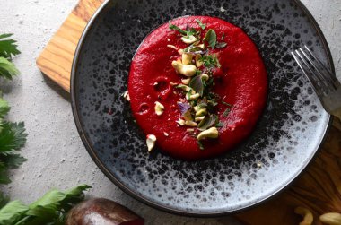 Maydanozlu pancar humusu, sarımsak ve siyah tabakta otlar..