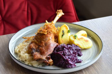 Kızarmış ördek bacağı, haşlanmış kırmızı lahana ve hamur tatlısı..