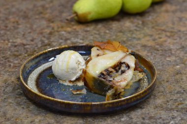 Hamur içinde fırında armut, bir tabakta tatlı, mermer bir masanın arkasında