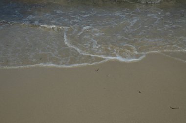 Sahilin kumlarında dalgalar ve köpükler, İspanya 'da Akdeniz, denizin ve gökyüzünün arka planında