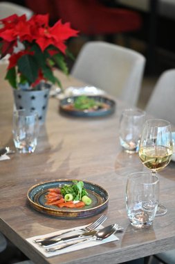 Çatal bıçaklı Noel masası, Noel süsü ve kırmızı şaraplı cam.