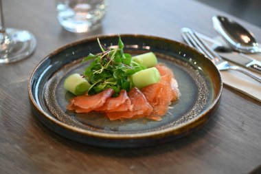 Avokado, domates, salatalık, salatalık, susam ve susamlı somon salatası siyah bir masada beyaz bir kasede..