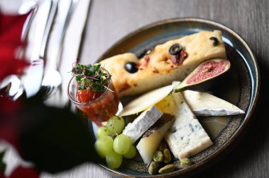 Peynir tabağında çeşitli peynirler, üzümler, incirler ve üzümler var..