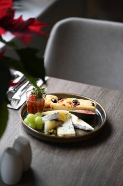 Peynir tabağında çeşitli peynirler, üzümler, incirler ve üzümler var..