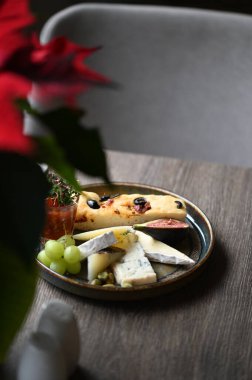 Peynir tabağında çeşitli peynirler, üzümler, incirler ve üzümler var..