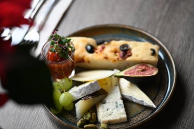 Peynir tabağında çeşitli peynirler, üzümler, incirler ve üzümler var..