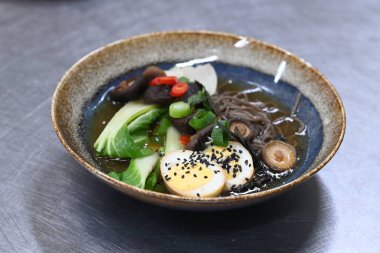 Sığır etli, sebzeli ve mantarlı Japon eriştesi Japon eriştesi çorbası mantarlı ve sebzeli siyah kase.