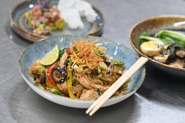 Tayland yemeği. Sebzeli kızarmış tavuk ve tabakta erişte..