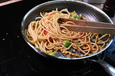 Siyah tavada tavuk ve sebzeli spagetti.