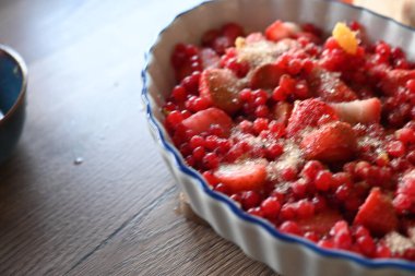 Bir kase lezzetli süzme peynir ve ahududu masanın üstünde.