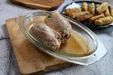 İçi doldurulmuş et rulosunun yakın plan çekimi, ikiye bölünmüş, bitkiler ve sebzelerle dolu lezzetli bir dolgu ortaya çıkarıyor..