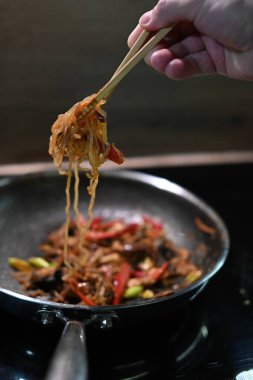 Şef tavada sebzeli kızarmış tavuk pişiriyor.