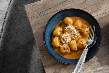 color photo of a dish of potato gnocchi sprinkled with parmesan, in a pepper sauce, with herbs, traditional homemade tasty food, close up view clipart