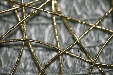 Soyut makro fotoğraf, yumuşak bokeh efektli parlak lifler yakalıyor. Altın iplikler ışığı güzel yansıtıyor, rüya gibi ve ruhani bir kompozisyon oluşturuyor.