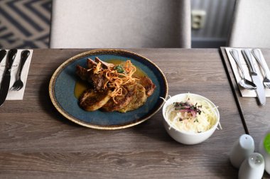 Kızarmış patatesli gözlemelerin yanında, bol soslu leziz bir domuz boynu. Yemek, ahşap bir restoran masasına yerleştirilmiş kırsal seramik bir tabakta zarif bir şekilde sunuluyor.