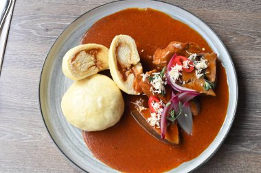 A traditional Czech dish, zabijakov gul, served in a restaurant on a rustic plate. This rich and hearty stew is made from a mix of pork meat, liver, and heart, slow-cooked with flavorful spices clipart