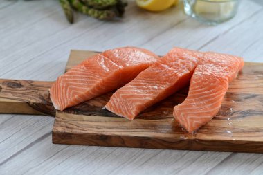 Yüksek kaliteli çiğ somon filetosu. Canlı turuncu bir tonu var. Açık arkaplanda güzelce yerleştirilmiş.