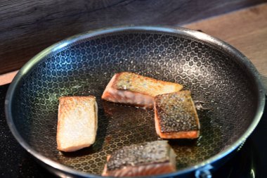 Kızartma tavasında cızırdayan bir somon filetosunun yakın çekimi, sulu dokusunu korurken çıtır çıtır bir altın kabuğu sergiliyor..