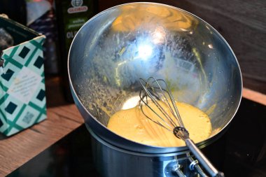 Gümüş bir karıştırma kasesinde Hollandaise sosu için yumurta hazırlama ve çırpma işlemi