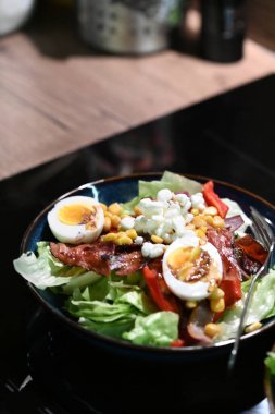 Domuz pastırmalı yumurta ve siyah tabakta sebze.