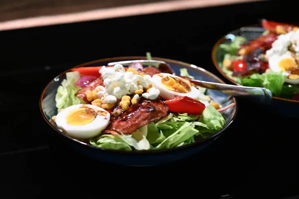 Siyah arka planda yumurta ve domatesli sağlıklı salata.