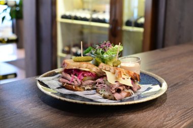 Yumuşak, dumanlı et, taze marul, sulu domates ve erimiş peynirle dolu lezzetli bir pastırmalı sandviç.. 