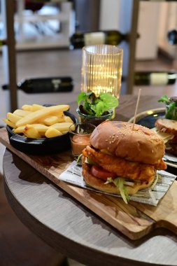 Masada kızarmış patates ve patates ile lezzetli bir burgerin yüksek açılı görüntüsü.