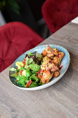 Tavuk göğsü, taze sebzeler ve restoranda bir tabakta salata.