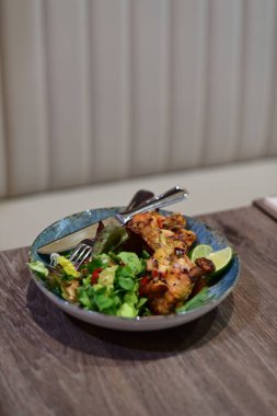 Sebze salatalı tavuk göğsü ve ahşap bir masada peynir.