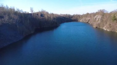  Çek Cumhuriyeti 'nin Kuzey Moravya şehrinde bulunan taşlı taş ocağının insansız hava aracı görüntüleri. Sahne nefes kesici ve güneşli gökyüzünün altında manzarayı yakalar. Kristal berraklığında mavi göl.