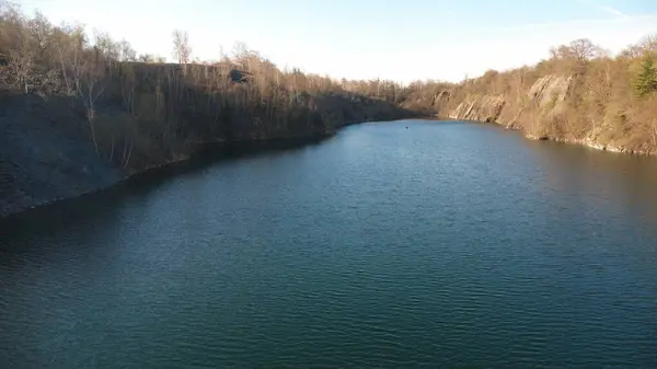 Çek Cumhuriyeti 'nin Kuzey Moravya şehrinde bulunan taşlı taş ocağının insansız hava aracı görüntüleri. Sahne nefes kesici ve güneşli gökyüzünün altında manzarayı yakalar. Kristal berraklığında mavi göl.