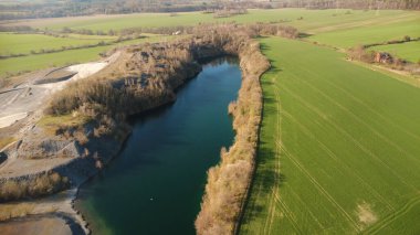 Çek Cumhuriyeti 'nin Kuzey Moravya şehrinde bulunan taşlı taş ocağının insansız hava aracı görüntüleri. Sahne nefes kesici ve güneşli gökyüzünün altında manzarayı yakalar. Kristal berraklığında mavi göl.