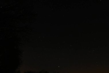 Yıldızlar arasında hızla ilerleyen parlak bir göktaşı içeren bahar gecesi gökyüzünün panoramik görüntüsü. 