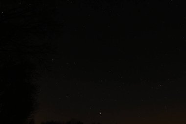 Yıldızlar arasında hızla ilerleyen parlak bir göktaşı içeren bahar gecesi gökyüzünün panoramik görüntüsü. 