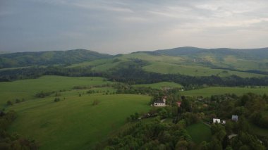 Çek Cumhuriyeti 'nin Hanuovice yakınlarındaki Vojtkov köyünün akşam manzarası. Ormanlar, yuvarlanan tepeler ve yumuşak akşam ışığında manzaralı kırsal manzarayla çevrili geleneksel bir kırsal bölge.