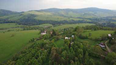 Çek Cumhuriyeti 'nin Hanuovice yakınlarındaki Vojtkov köyünün akşam manzarası. Ormanlar, yuvarlanan tepeler ve yumuşak akşam ışığında manzaralı kırsal manzarayla çevrili geleneksel bir kırsal bölge.