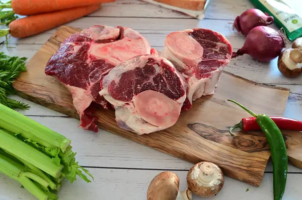 Kesme tahtasındaki çiğ et ve sebzeler.