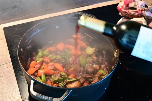 Tencerede şarap ile sebze pişirmek.