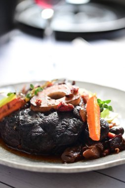 Sebzeli leziz et bifteği ve ahşap zemin üzerinde otlar.