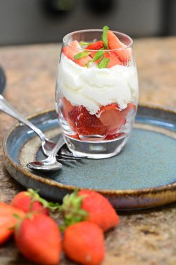 Krem şantili taze çilekli tatlı ve beyaz arka planda nane şekeri. Kapat.