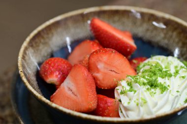 Tahta arka planda taze çilek ve krem şanti.