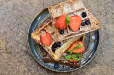 Renkli çan biberlerinin üst görüntüsü. İçi öğütülmüş et, pilav ve karışık sebzelerle doldurulmuş. Seramik bir fırın kabına dizilmiş.. 