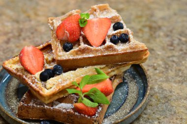 Renkli çan biberlerinin üst görüntüsü. İçi öğütülmüş et, pilav ve karışık sebzelerle doldurulmuş. Seramik bir fırın kabına dizilmiş.. 