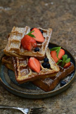 Siyah tabakta yaban mersinli ve çilekli waffle..