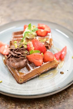 Çilekli çikolatalı waffle, çikolata ve nane yapraklı.