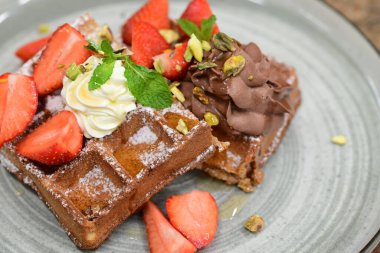 Çilekli çikolatalı waffle ve çikolata şurubu.