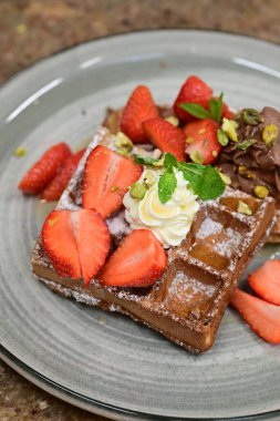Siyah arka planda taze çilek ve naneli çikolatalı pastanın yakın plan fotoğrafı.