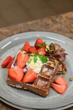 Çilekli çikolatalı waffle, krema ve dondurma.