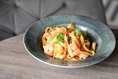 Beyaz tabakta karides ve fesleğenli spagetti.