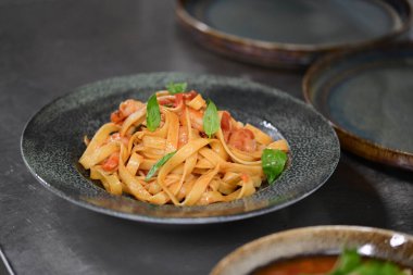 Somon ve sebzeli leziz spagetti karanlık masada, yakın plan.